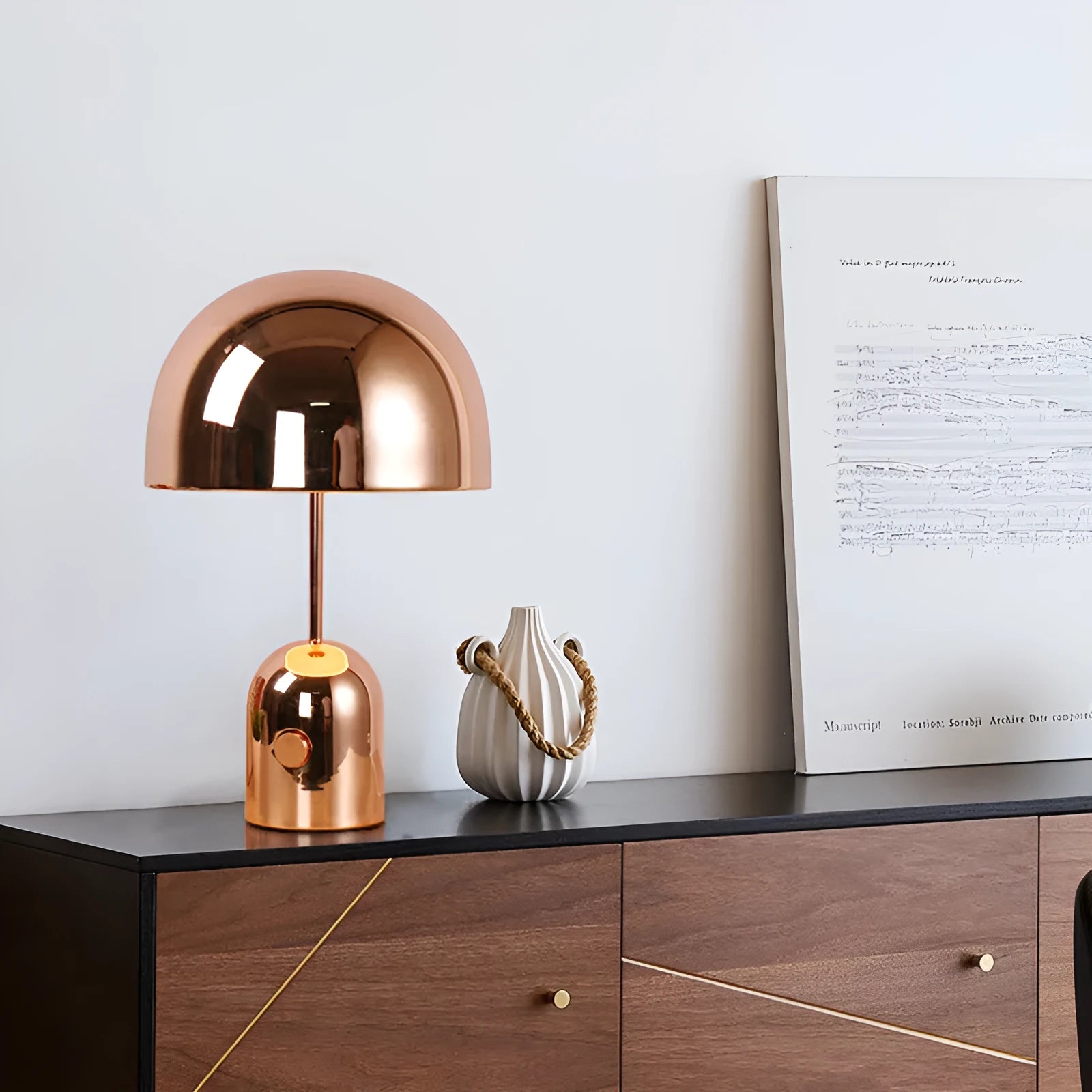 Mushroom shaped metal table lamp in rose gold finish on a wooden surface.