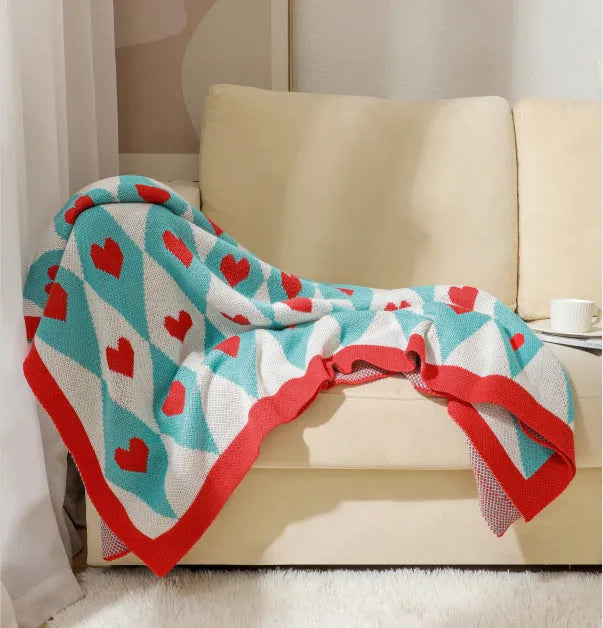 Beige and orange bohemian-style acrylic sofa blanket with tassel fringe on a grey sofa.