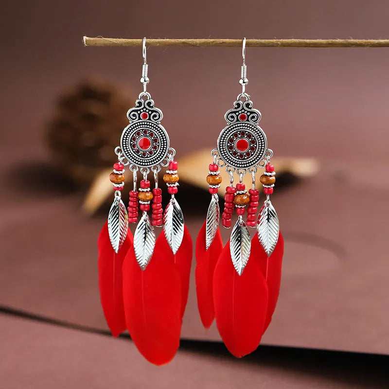 A pair of round drop leaf-shaped feather earrings in a chosen colour, showing Bohemian pattern details.