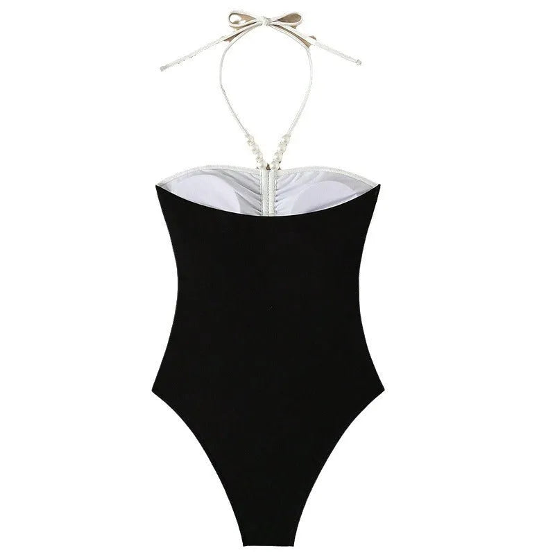 Black and white women's one-piece swimsuit with slim fit and pearl spaghetti straps on a mannequin.