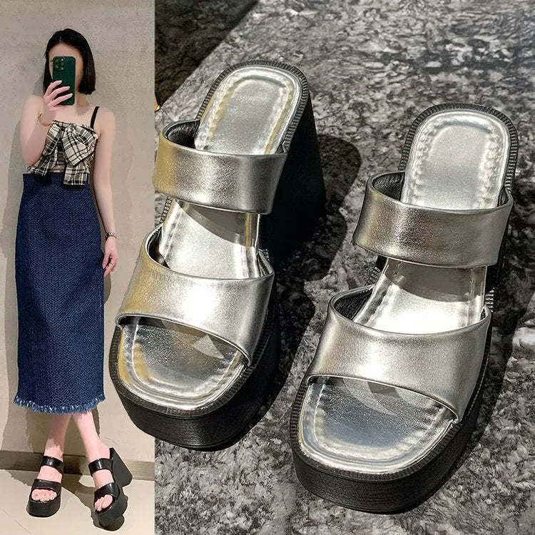 Women's black wedge platform slippers with a square toe on a white background.