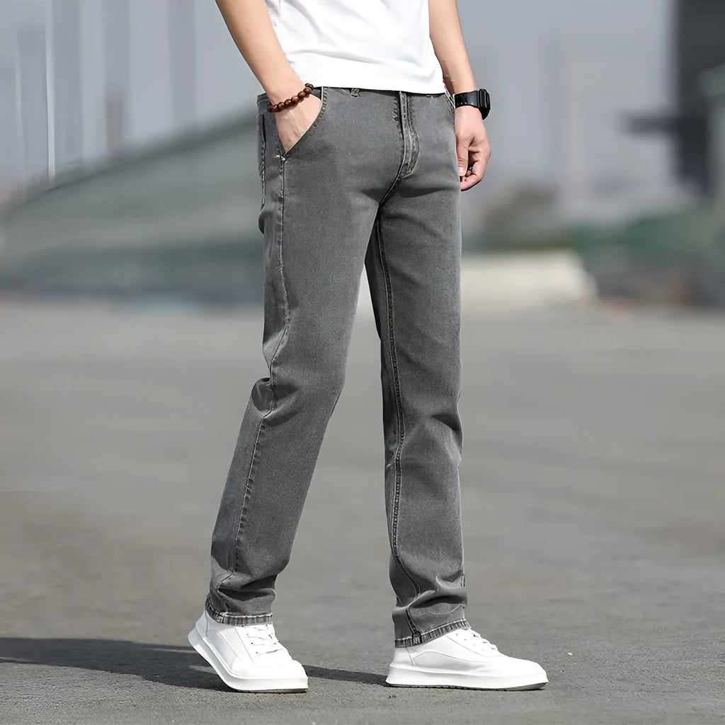 Man wearing smoky grey straight leg men's jeans with a low waist and zip fly.