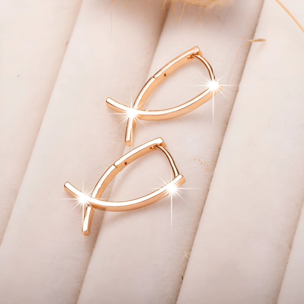 A pair of rose gold cross-shaped earrings made from copper on a white background.