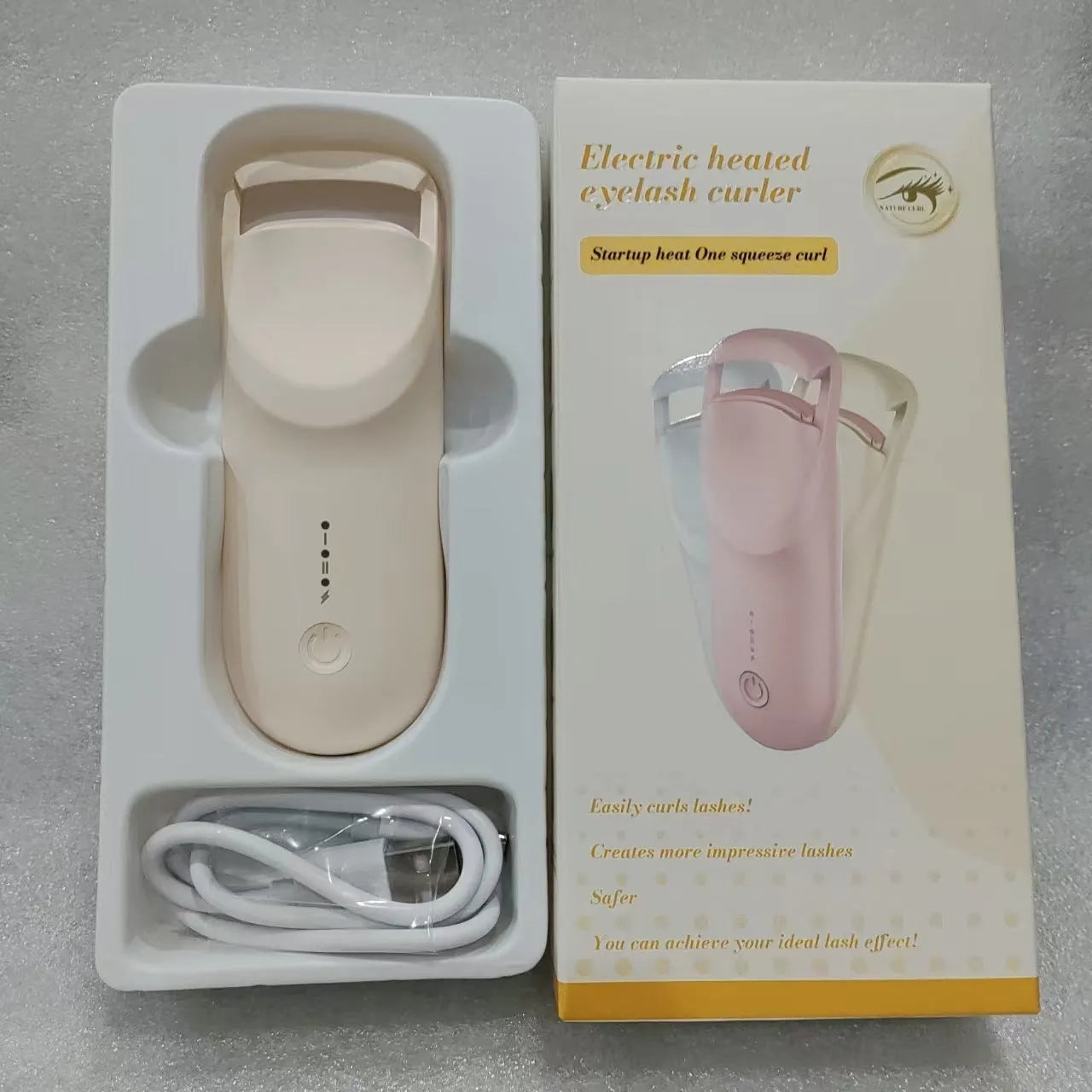Plastic electric heating eyelash curler with USB cable in cream white, pink, or apricot.