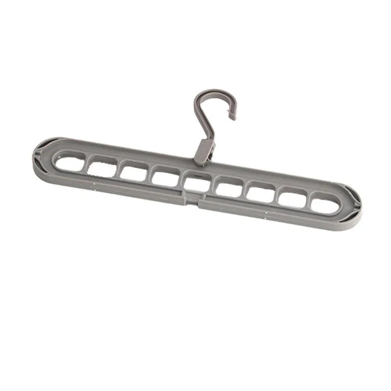 Green plastic multifunctional hanger with nine arms for folding trousers, shown hanging on a rail.