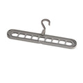 Green plastic multifunctional hanger with nine arms for folding trousers, shown hanging on a rail.