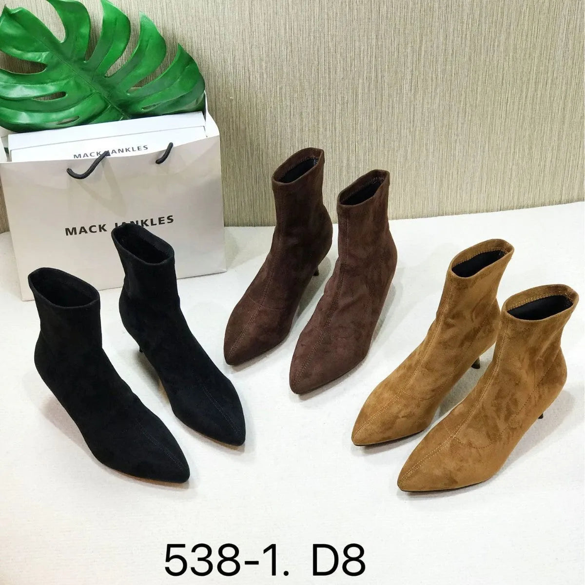 Black pointed toe ankle boots with a high stiletto heel on a woman's foot.