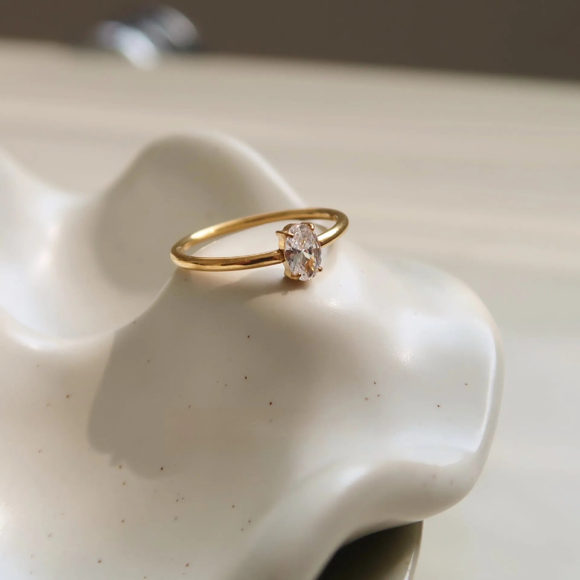 Golden electroplated stainless steel love heart ring and oval ring for women on a plain background.