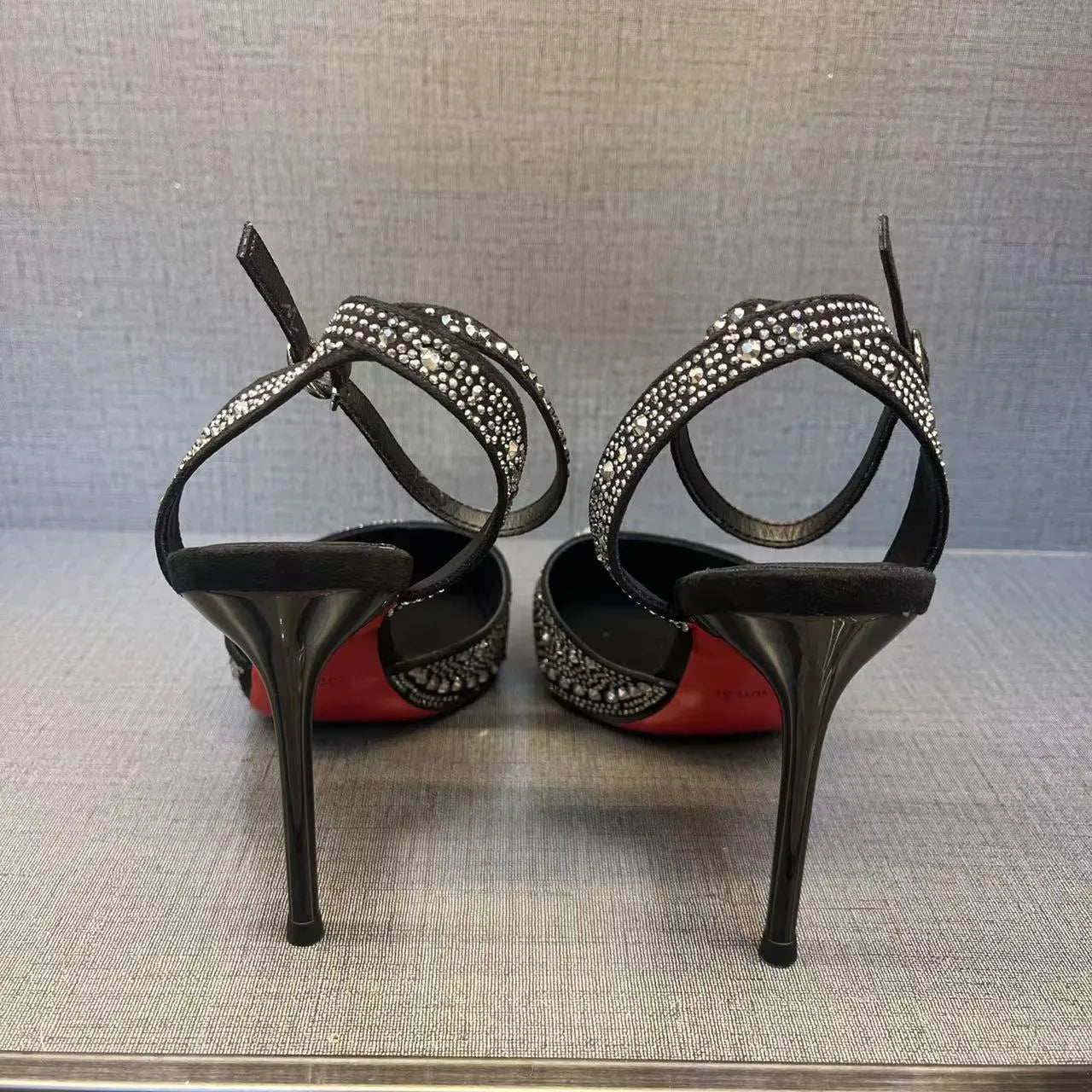 Women's black and silver hollow high heels with red stiletto soles and pointed toes.