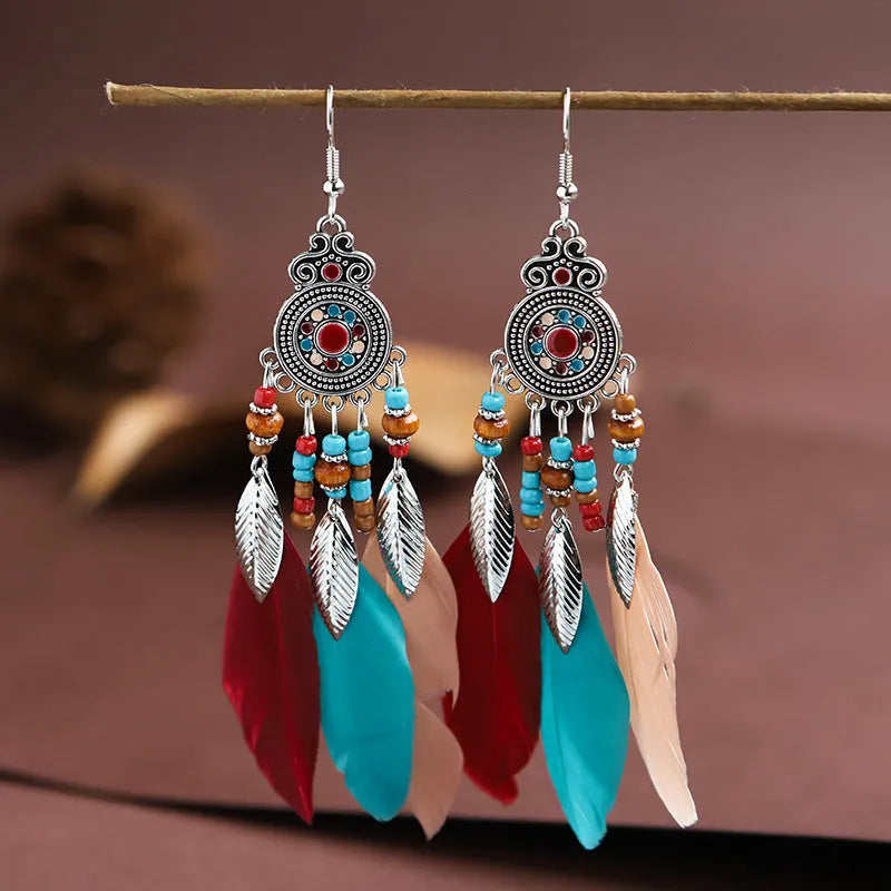 A pair of round drop leaf-shaped feather earrings in a chosen colour, showing Bohemian pattern details.
