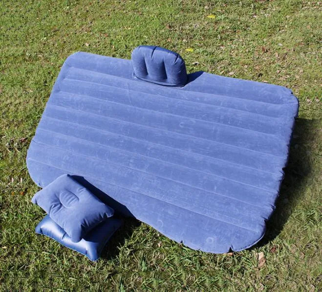 Black inflatable car bed with flocked surface and two pillows, shown inside a vehicle.