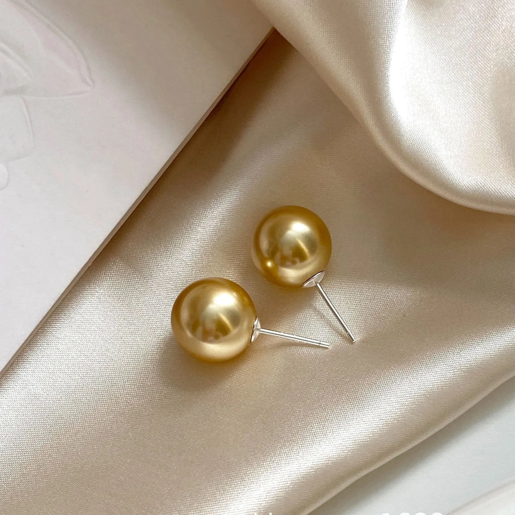 A pair of large geometric pearl stud earrings with a retro eight awn star motif on a silver setting.