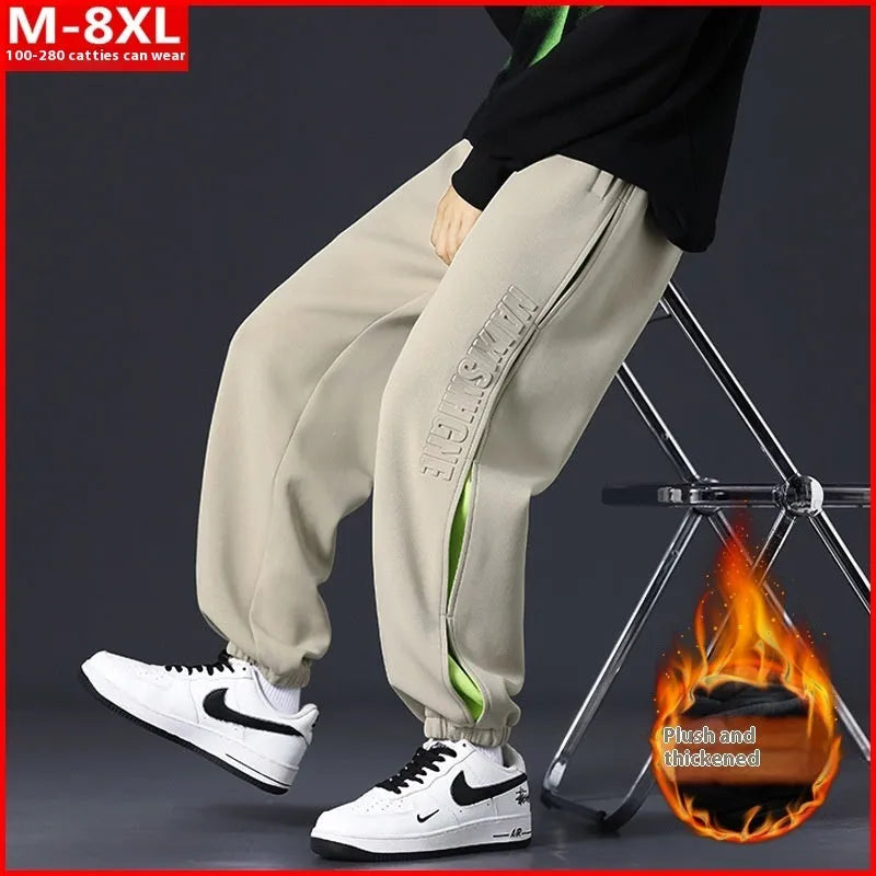 Man wearing loose grey-green trousers with stitching print detail and ankle banding.