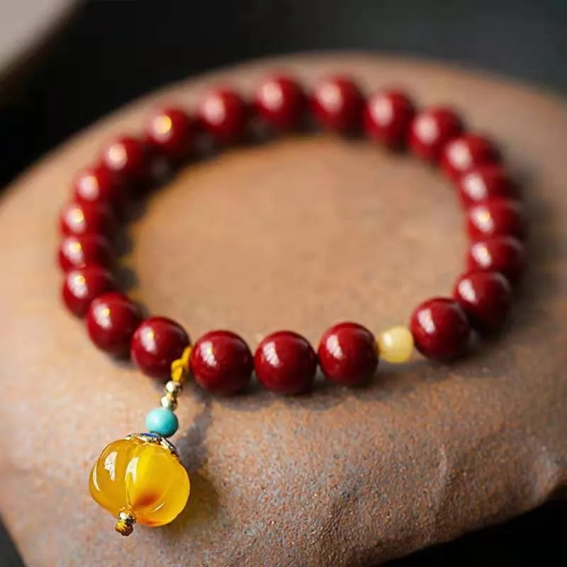Gold cinnabar and copper bead bracelet in a wave shape on a wrist.