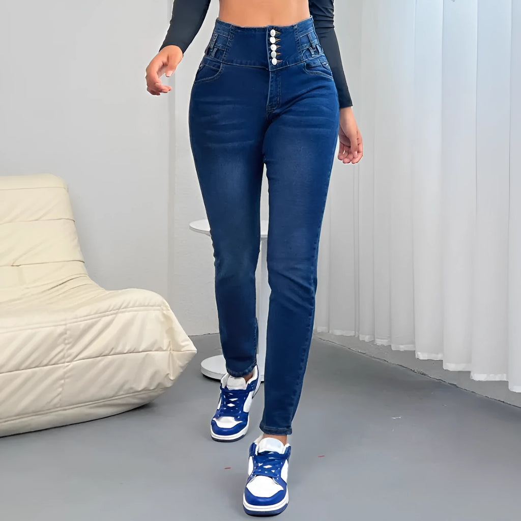 Dark blue women's straight-leg skinny denim trousers with zipper and button detail on a hanger.