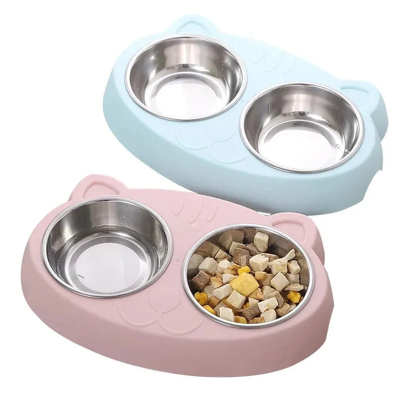 Blue plastic double bowl pet feeding tray for cats and dogs with non-slip rubber feet on a floor.