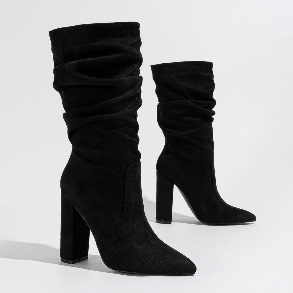 Women's black suede knee-high boots with a chunky high heel and pointed toe on a plain background.