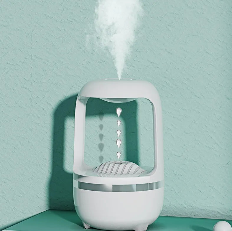 White anti-gravity water droplet humidifier on a wooden desk with visible mist and upward-flowing water beads.