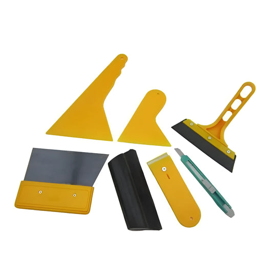 Seven-piece car film tool set with scrapers, knives, and a pressing block on a work surface.