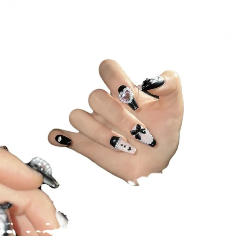 Black and pink heart hand-painted artificial nails with bow detailing in mid-length cat's eye design