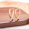 A pair of rose gold cross-shaped earrings made from copper on a white background.
