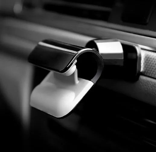 Black gravity car phone holder with 360-degree rotating head mounted on a car air vent.