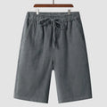 Men's beige linen casual shorts with loose cropped fit and elastic waistband laid flat