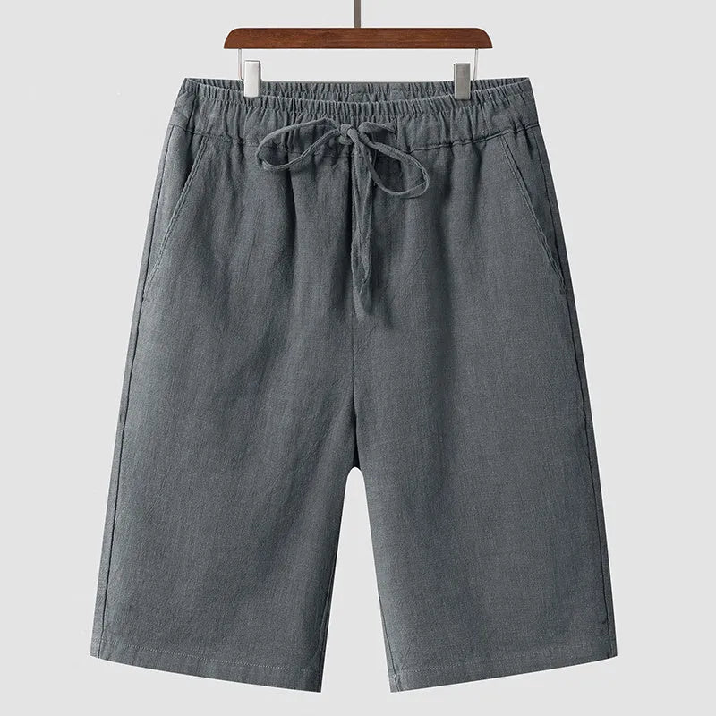Men's beige linen casual shorts with loose cropped fit and elastic waistband laid flat