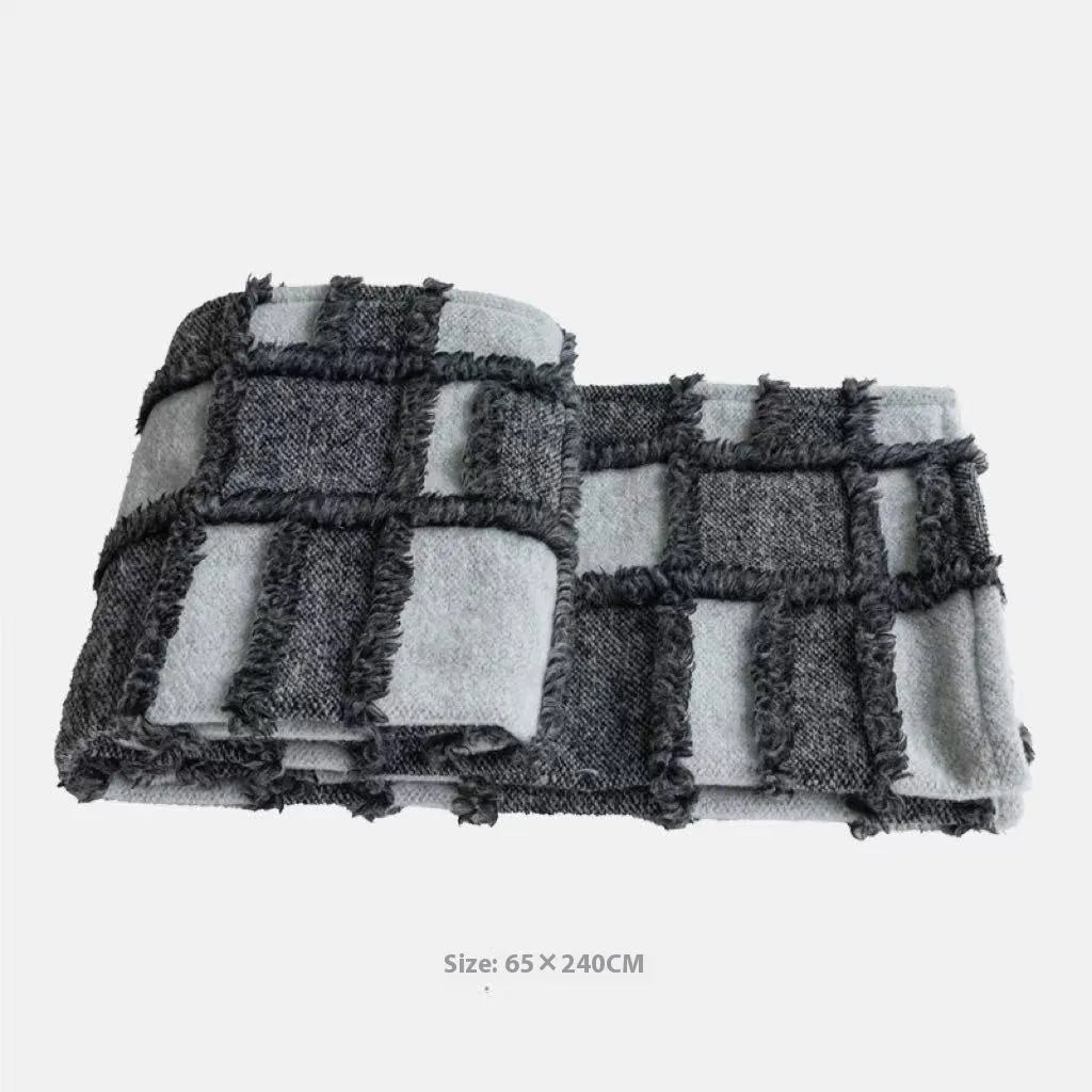Grey and white plaid polyester bed runner blanket with matching pillowcase and leather round pillow on a double bed.
