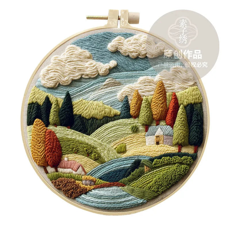 Embroidery kit with printed landscape fabric, thread, bamboo frame, and needles arranged for DIY cloth art