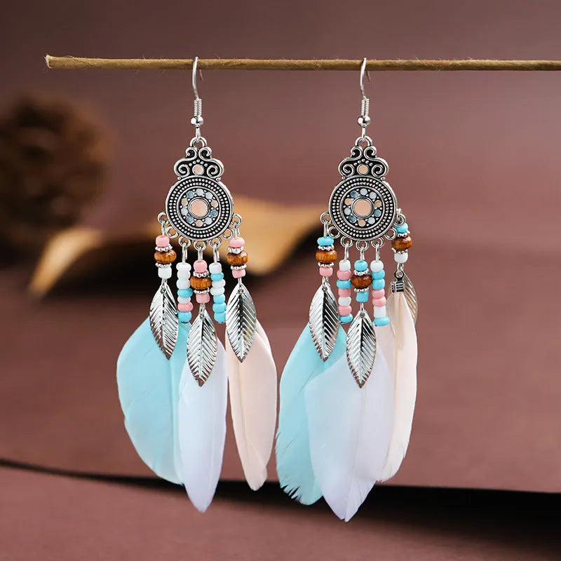 A pair of round drop leaf-shaped feather earrings in a chosen colour, showing Bohemian pattern details.