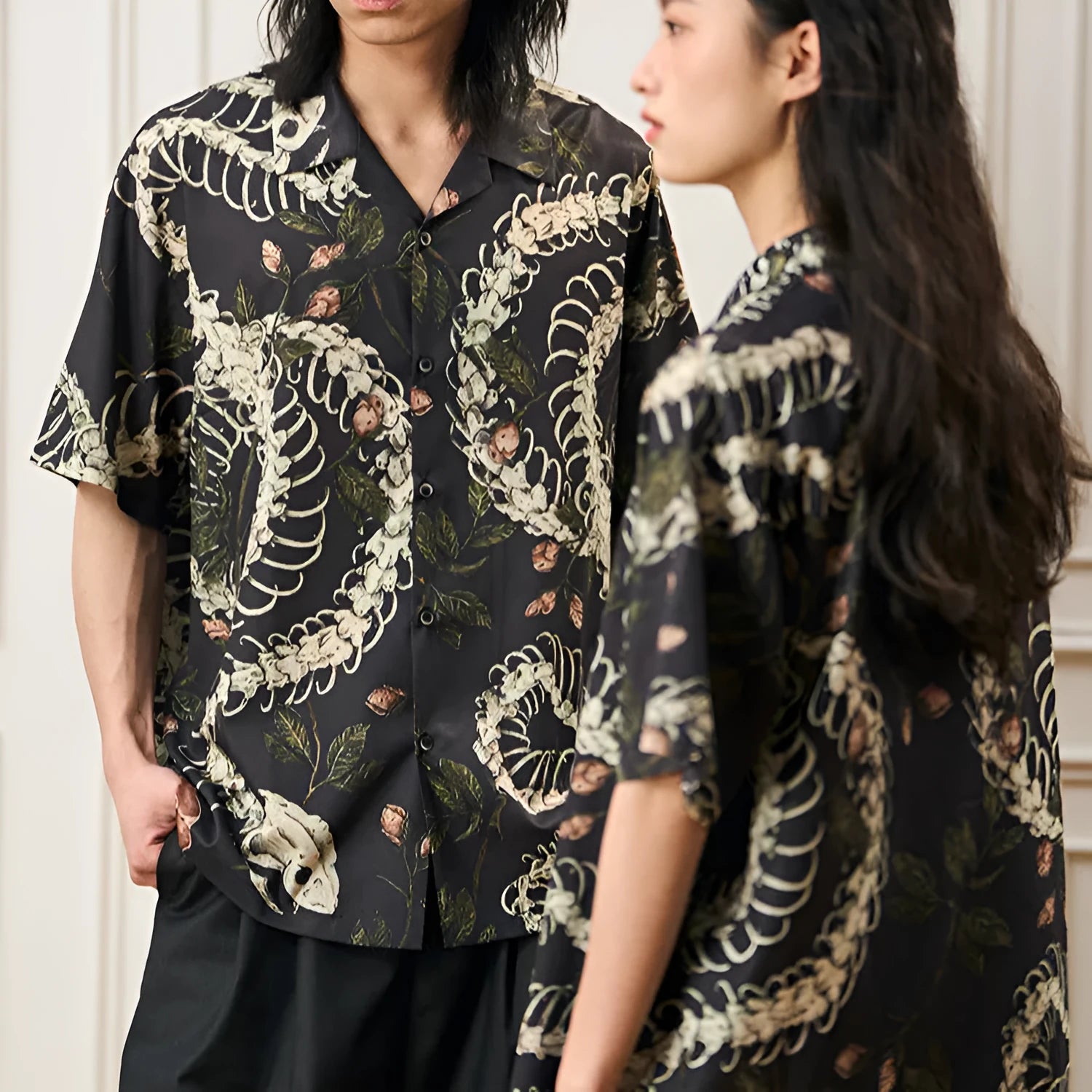 Man wearing a loose fit short sleeve Cuban collar shirt with a snake bone and floral pattern print.