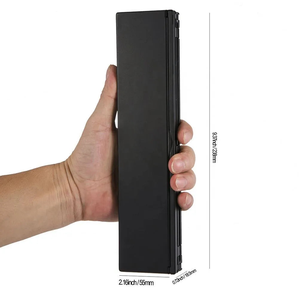 Black folding wireless Bluetooth keyboard unfolded next to tablet showing mini keyboard size