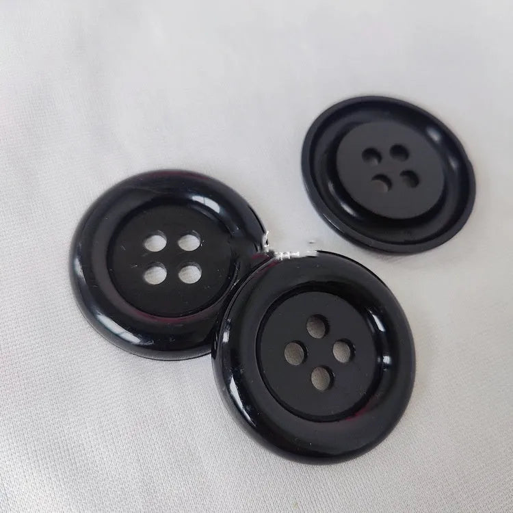 Oversized round plastic button with four holes in various colours and sizes from 38mm to 70mm.