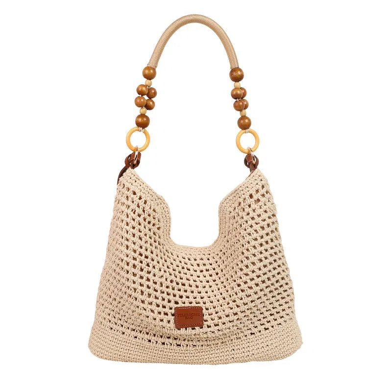 Knitted bucket-shaped tote beach bag with crossbody strap, shown in black, featuring contrasting stitching.