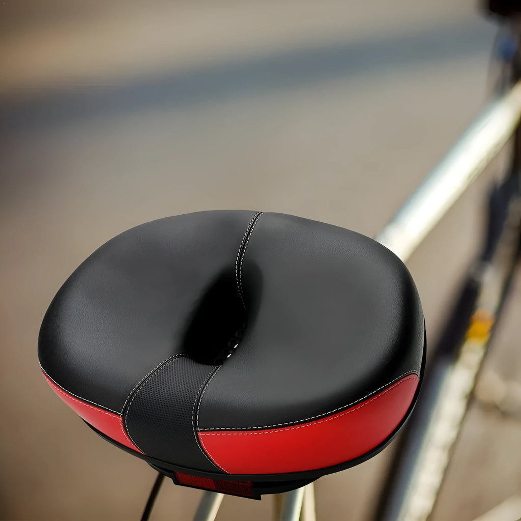 Large red bicycle saddle with reflective stickers, showing thickened design and shock absorber.