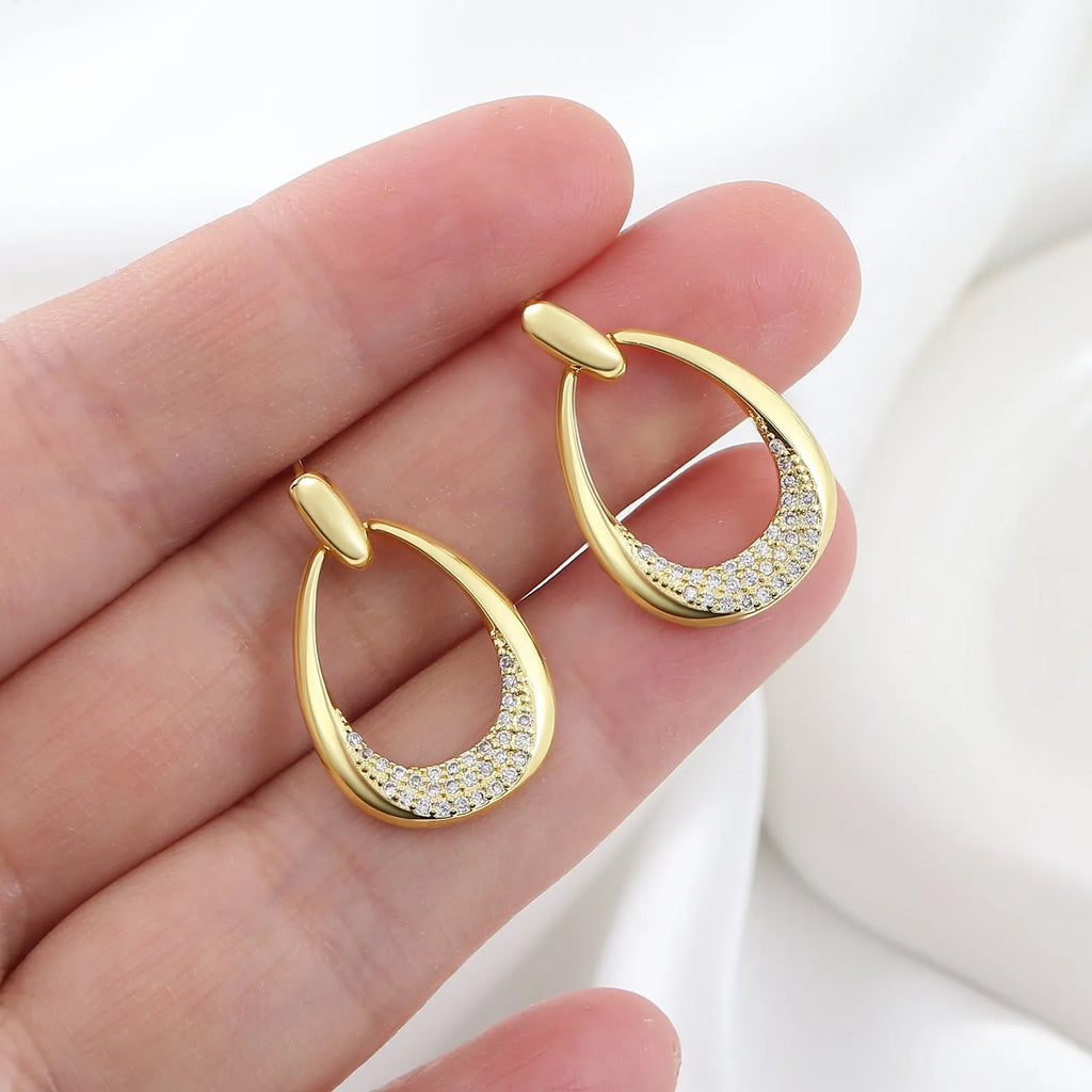 Yellow gold geometric drop earrings for women with round and oval elements, shown with handbag packaging.