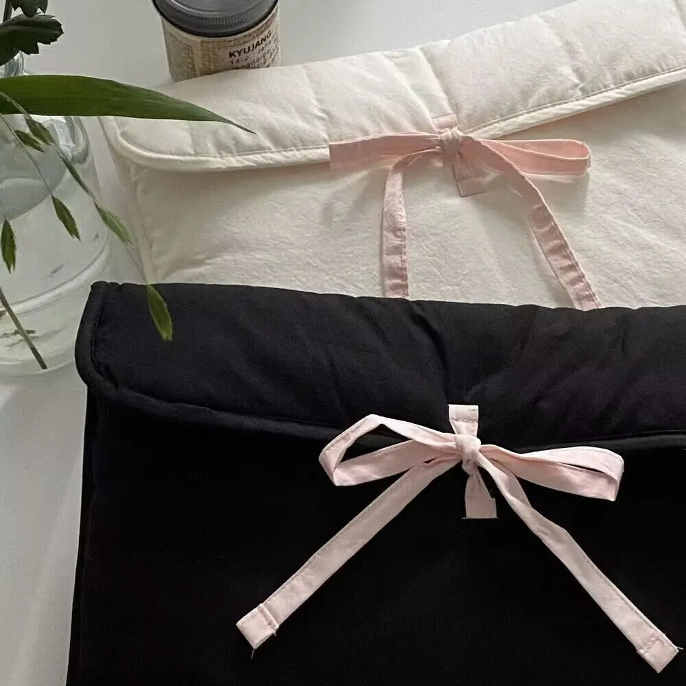 Women's black quilted computer bag with ballet bow detail showing striped nylon lining