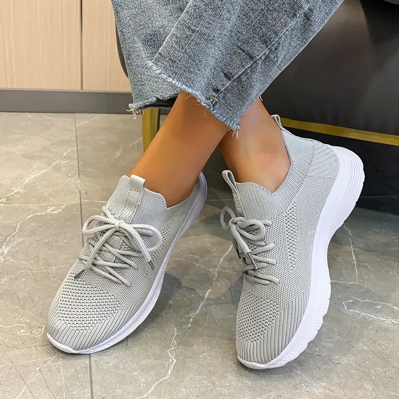 Women's mesh running shoes in creamy white with Flyknit upper and flat rubber sole