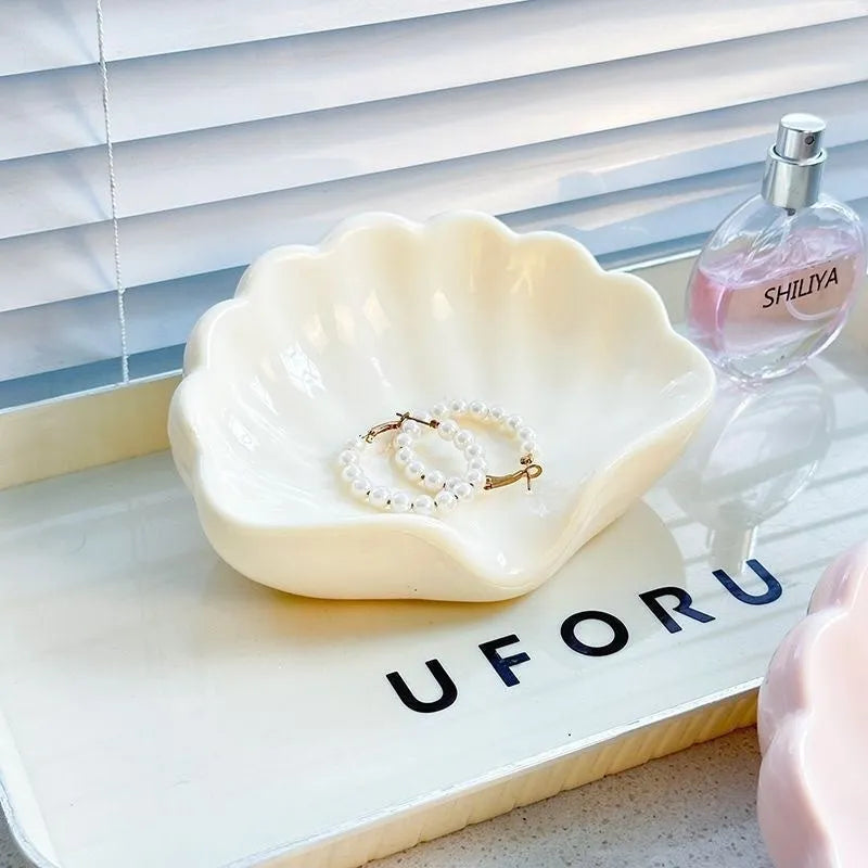 White shell-shaped plastic soap dish on a bathroom countertop.