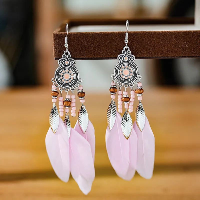 A pair of round drop leaf-shaped feather earrings in a chosen colour, showing Bohemian pattern details.