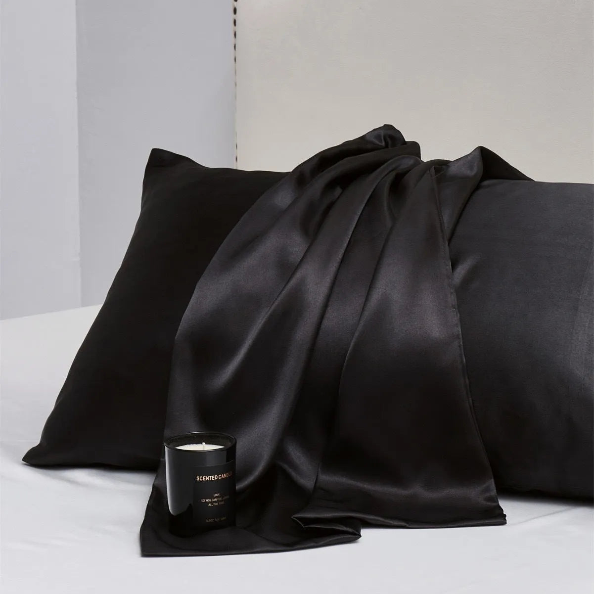 A pair of solid colour satin pillowcases in various colours and sizes on a bed.