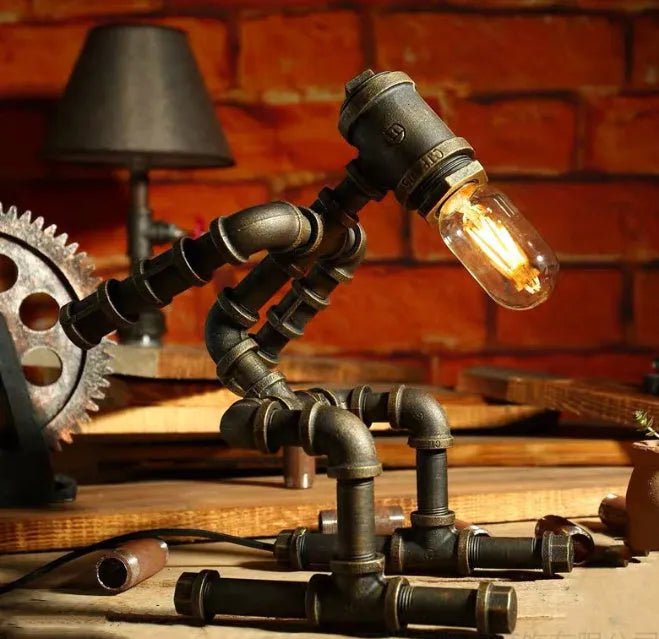 Green bronze vintage industrial robot desk lamp with iron pipe design on a wooden table.