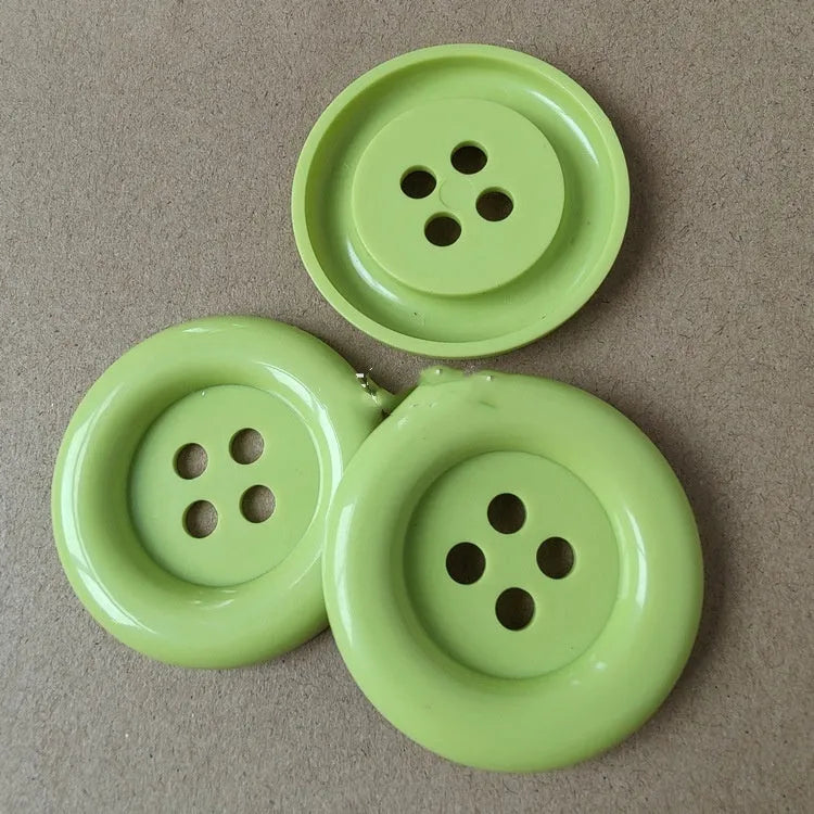 Oversized round plastic button with four holes in various colours and sizes from 38mm to 70mm.