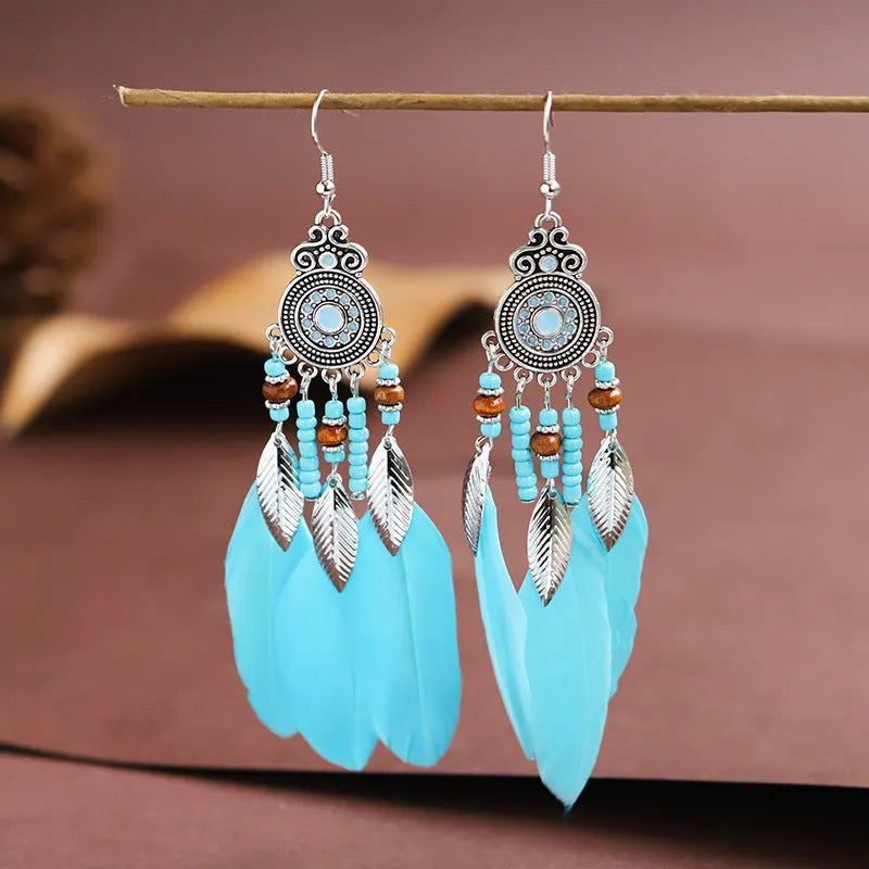 A pair of round drop leaf-shaped feather earrings in a chosen colour, showing Bohemian pattern details.
