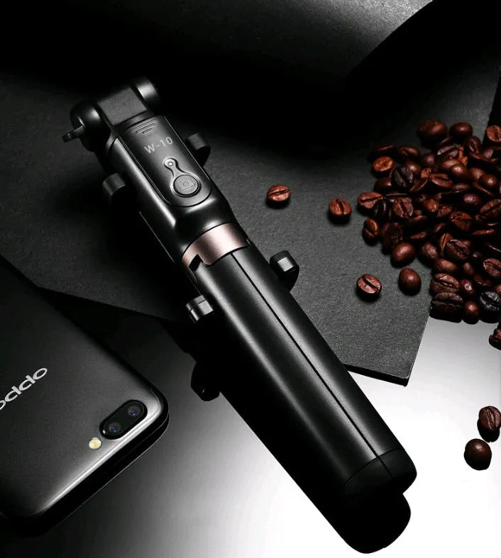 Black Bluetooth selfie stick tripod with remote control extended next to mobile phone