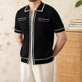 Man's slim fit black knitted polo shirt with lapel collar and short sleeves on a hanger.