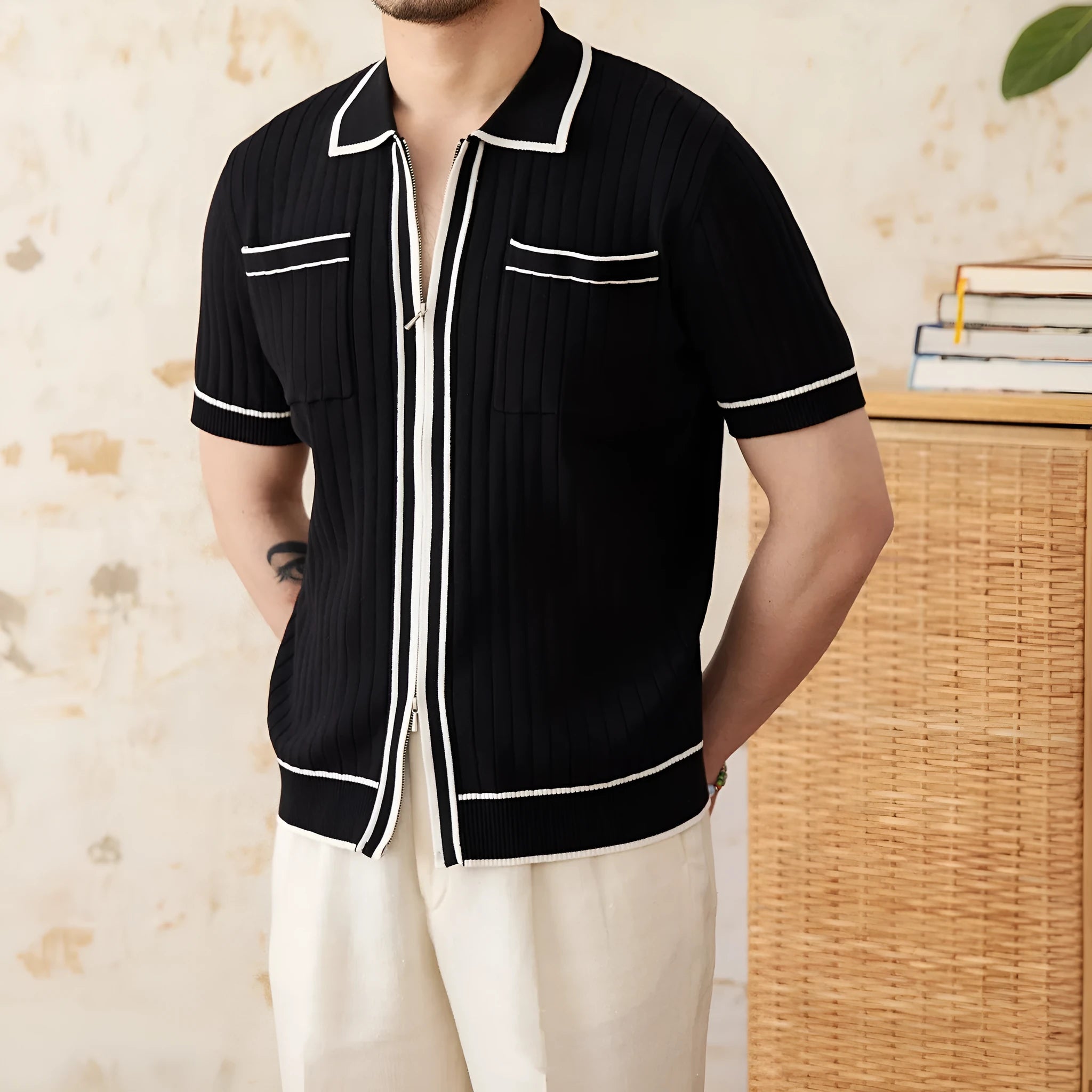 Man's slim fit black knitted polo shirt with lapel collar and short sleeves on a hanger.