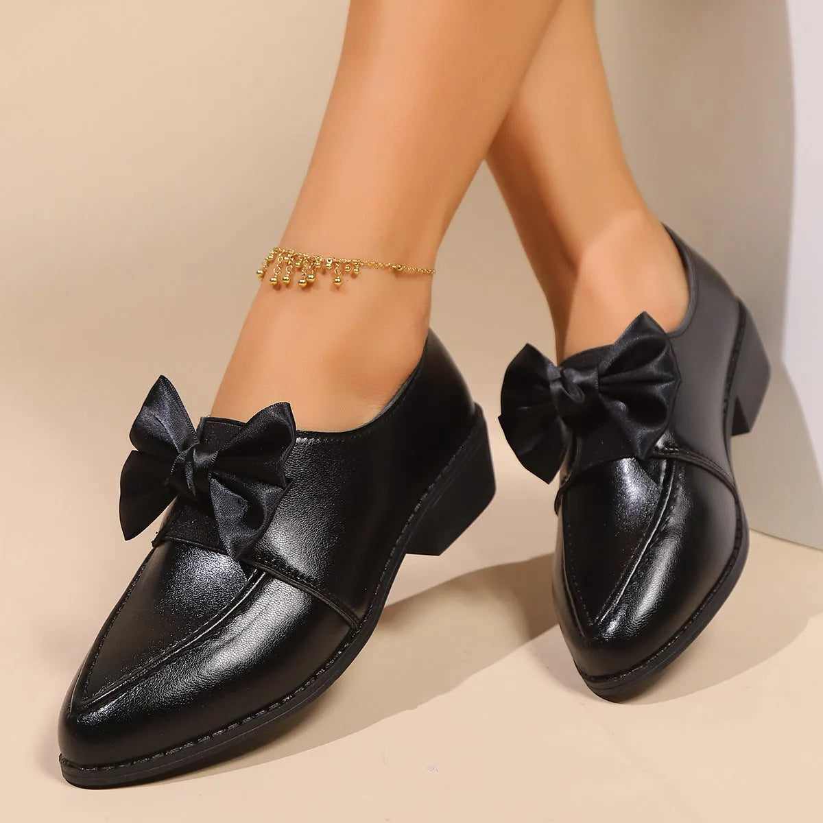 Women's brown leather-look shoes with a decorative bow detail on a flat rubber sole