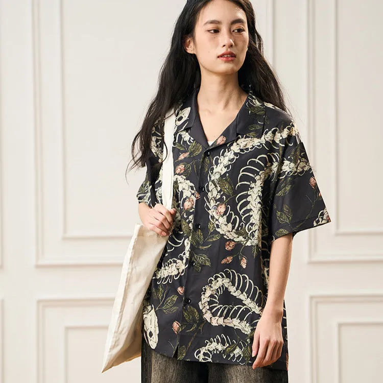Man wearing a loose fit short sleeve Cuban collar shirt with a snake bone and floral pattern print.